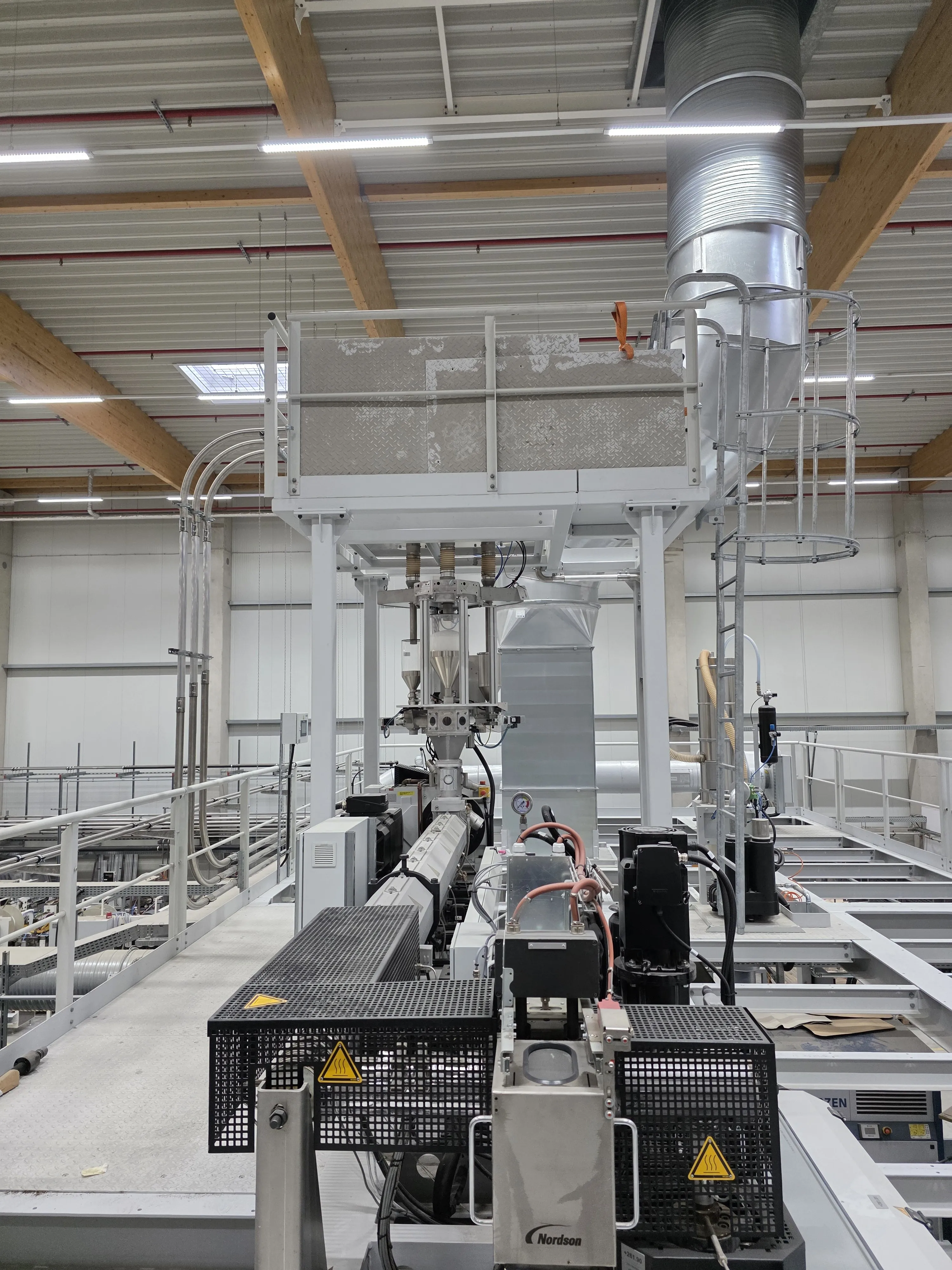 Extruder on the platform, dosing hoppers above, Nordson unit in front